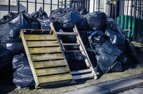 Bags of junk and broken pallets on corner of street to be removed