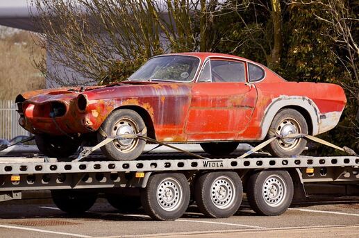Old Junk red car on flatbed truck being removed